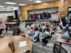 Board member Chad Crabb reading to laughing and smiling Four Mile students