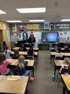 Board member Tracy Dawson wearing a Cat in the Hat hat, reading to Four Mile students