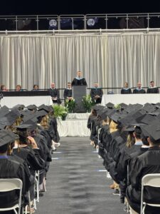 Dirk Halupnik speaking at 2026 Graduation center aisle