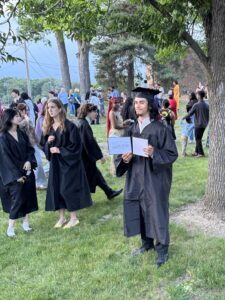 Graduate standing by tree after Graduation 2026