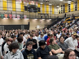 Sophomore/Junior waving to friend at Honors Assembly