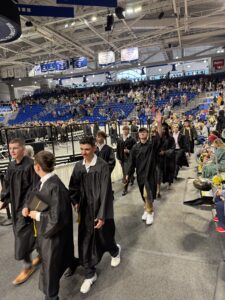 Graduate waving to family as class exits ceremony 2026