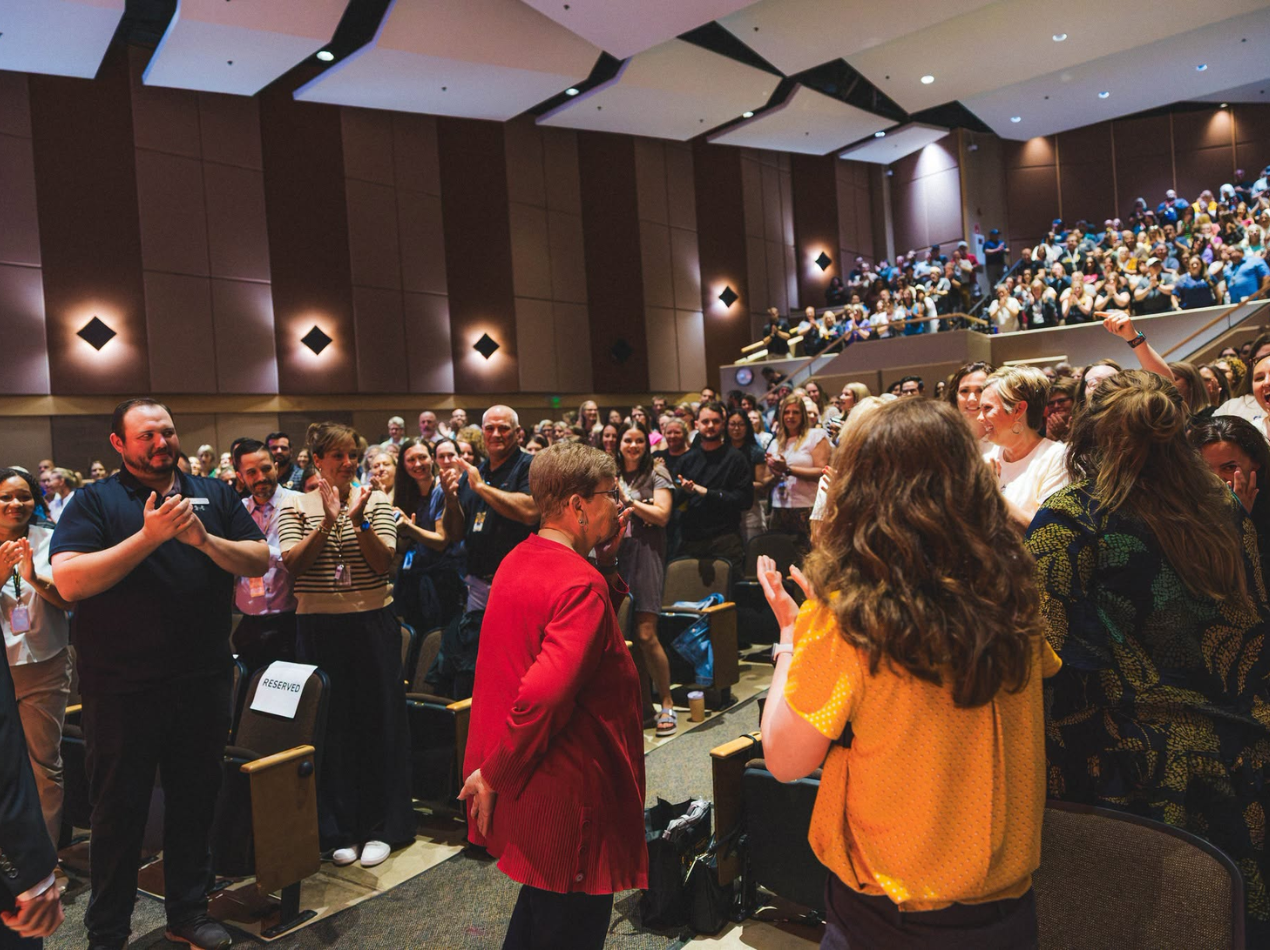 Denise Gulling, SEP teacher, stands to be recognized with a standing ovation during the all-staff welcome back.