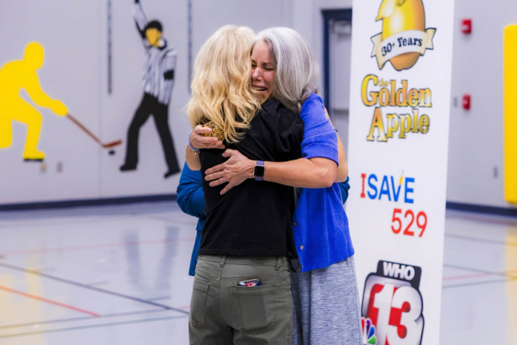 Mrs. Kathy Hoyt hugs co-teacher during her WHO-13 Golden Apple award ceremony.